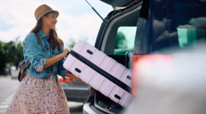 Person on holiday loading suitcase in to car boot